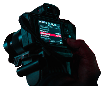 A DSLR held in one hand with its exposure menu open, showing the recording settings used for Lightboard filming