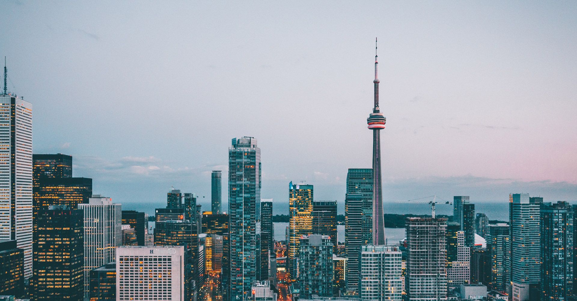 The Toronto skyline and the CN Tower at dusk, with Lake Ontario behind