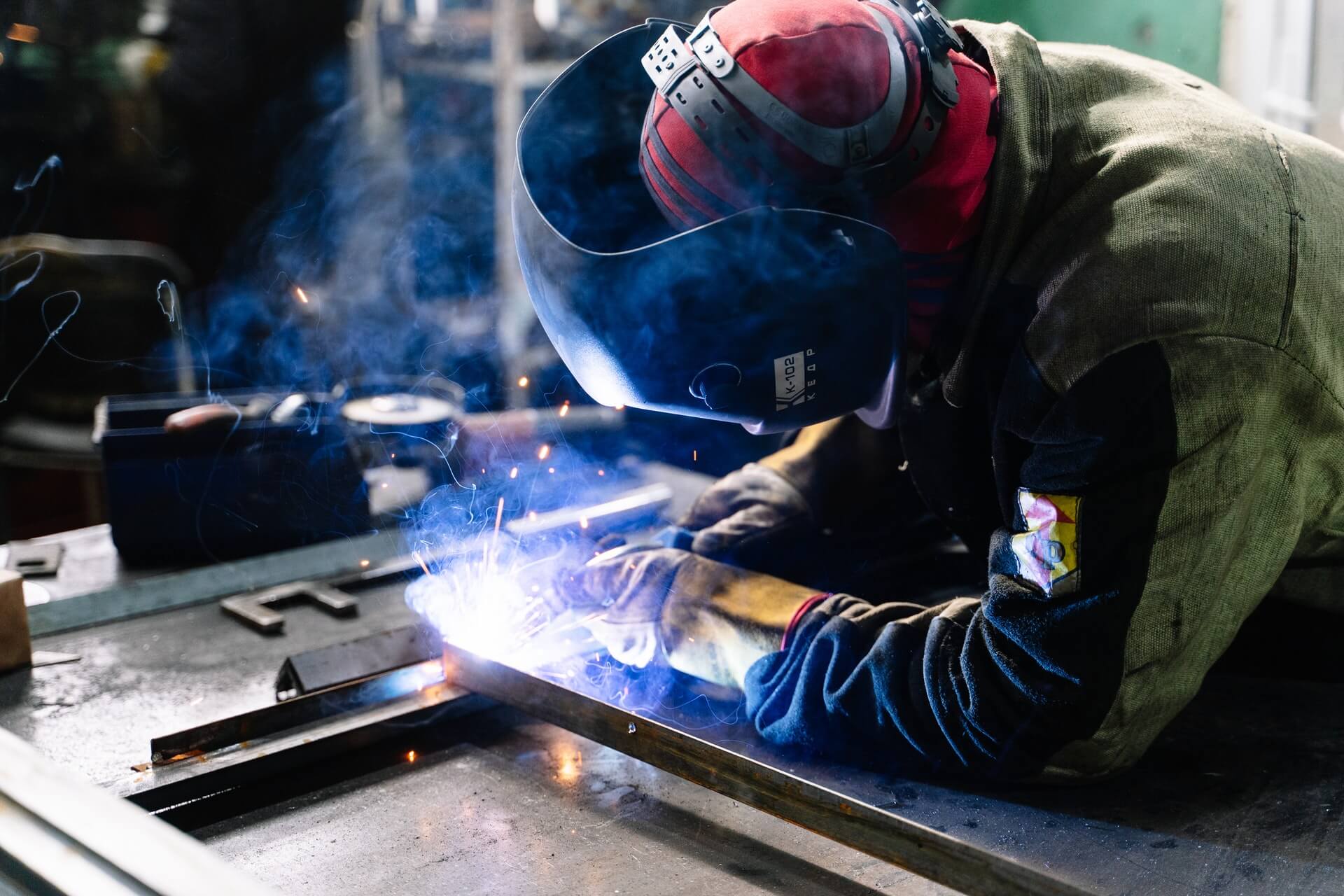 A fabricator welding a steel frame, sparks lighting up the workbench