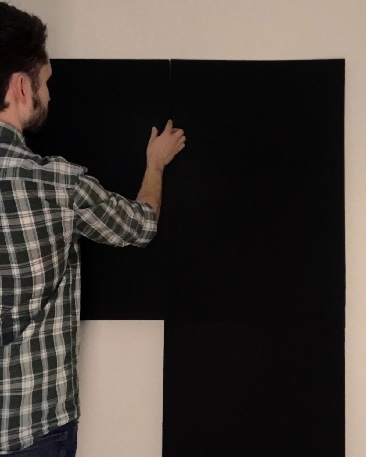 Man mounting black backdrop onto a wall