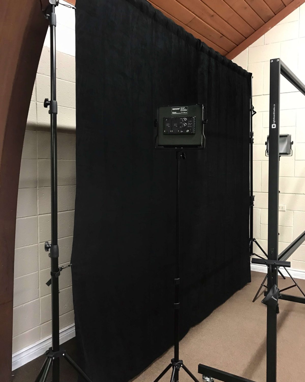 Standalone black backdrop fabric product side view with studio lights and lightboard